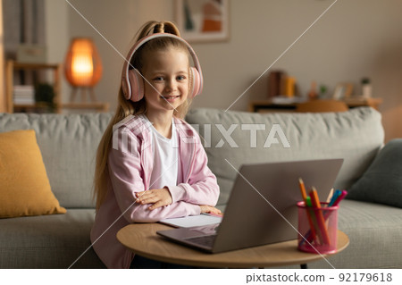 Cute Schoolgirl Using Laptop Wearing Pink Headphones Sitting At Home Cute Schoolgirl Using Laptop Wearing Pink Headphones Sitting At Home 92179618
