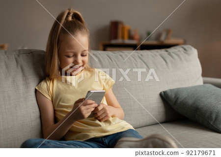 Happy Little Girl Using Smartphone Playing Mobile Game At Home 92179671