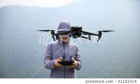 Woman remotel control a flying drone in spring forest Woman remotel control a flying drone in spring forest 92181024