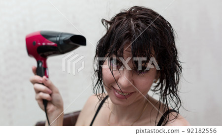 Woman blow-drying her hair after morning shower Woman blow-drying her hair after morning shower 92182556