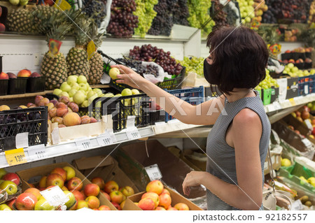 Woman buyer chooses apricots in the store Woman buyer chooses apricots in the store 92182557