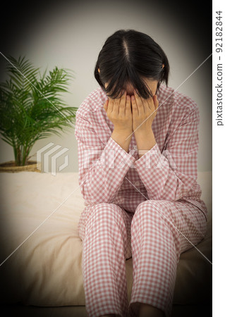 Middle-aged woman in pajamas mourning in the bedroom Middle-aged woman in pajamas mourning in the bedroom 92182844