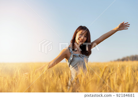 Beautiful and happy asian woman enjoying life in barley field at sunset. 92184681