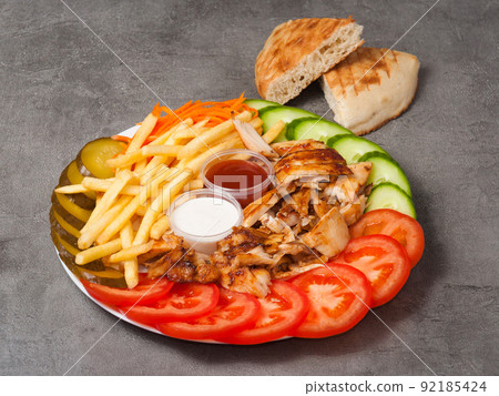 shawarma on a plate with french fries and sauce on a gray background shawarma on a plate with french fries and sauce on a gray background 92185424