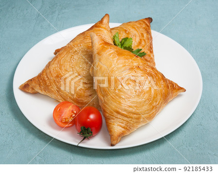 three samsas on a white plate on a blue background 92185433