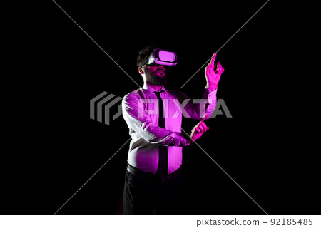 Businessman Using Virtual Reality Goggles Gesturing While Taking Professional Training. Light Falling On Man Experiencing Simulator And Presenting Modern Technology. Businessman Using Virtual Reality Goggles Gesturing While Taking Professional Training. Light Falling On Man Experiencing Simulator And Presenting Modern Technology. 92185485