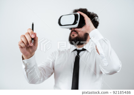 Standig Man Holding Pen To Point Important Messages And Wearing Vr Glasses. Businessman Having Virtual Reality Eyeglasses And Pointing On Crutial Informations. 92185486