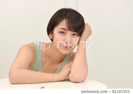 一個微笑的年輕女子在室內放鬆的吊帶背心的特寫鏡頭 一個微笑的年輕女子在室內放鬆的吊帶背心的特寫鏡頭 92185501