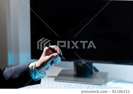 Businesswoman Holding Pen And Pointing On Important Messages On Table With Computer And Keyboard. Woman Presenting Crutial Information With One Hand. Businesswoman Holding Pen And Pointing On Important Messages On Table With Computer And Keyboard. Woman Presenting Crutial Information With One Hand. 92186252