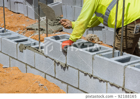 On a construction site, a mason is in the process of erecting a wall of aerated concrete blocks On a construction site, a mason is in the process of erecting a wall of aerated concrete blocks 92188165
