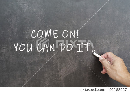Male hand writes in white chalk pencil the word come on you can do it. 92188937