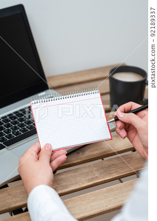 Businesswoman Holding Pen And Notepad With Important Message On Table With Lap Top And Coffee. Woman Presenting Crutial Information On Paper On Desk With Computer And Cup. Businesswoman Holding Pen And Notepad With Important Message On Table With Lap Top And Coffee. Woman Presenting Crutial Information On Paper On Desk With Computer And Cup. 92189337
