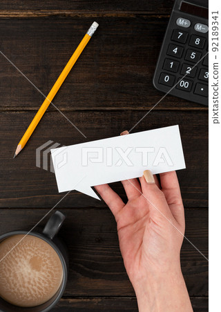 Hand Of Woman Having Thought Bubble Sheet With Coffee Cup And Stationery Over Wooden Background. Businesswoman Holding Blank Paper With Copy Space For Business Branding. Hand Of Woman Having Thought Bubble Sheet With Coffee Cup And Stationery Over Wooden Background. Businesswoman Holding Blank Paper With Copy Space For Business Branding. 92189341