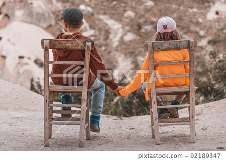children sitting on wooden chairs holding hands children sitting on wooden chairs holding hands 92189347