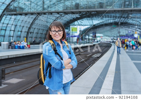 Woman passenger on railway platform inside station, with crossed arms looking at camera Woman passenger on railway platform inside station, with crossed arms looking at camera 92194108