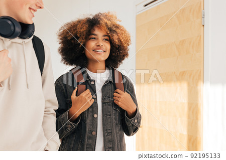 Young guys in casuals walking in college corridor and smiling 92195133