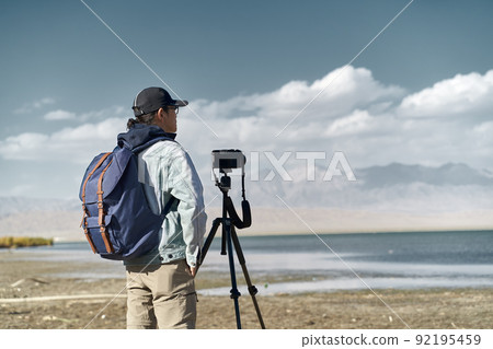 asian photographer standing by a lake looking at view observing 92195459