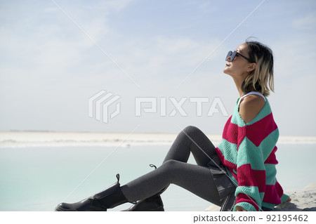 side view of asian woman tourist sitting by a salt lake looking at view side view of asian woman tourist sitting by a salt lake looking at view 92195462