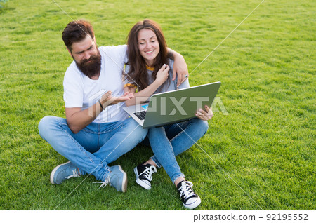 Cheerful couple watching series laptop outdoors, have fun concept Cheerful couple watching series laptop outdoors, have fun concept 92195552