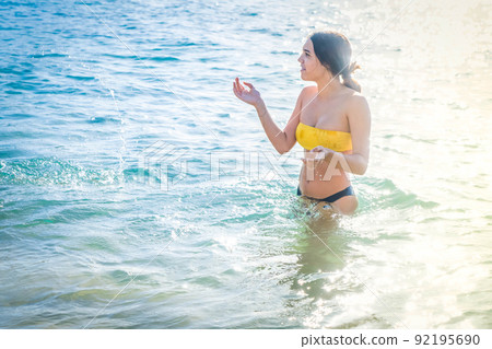 Young happy woman in bikini swimsuit swimming in sea Young happy woman in bikini swimsuit swimming in sea 92195690