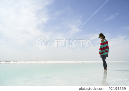 asian woman standing in a salt lake looking down at the water 92195869