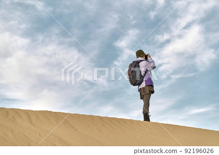 asian woman photographer standing on top of a sand dune taking a picture asian woman photographer standing on top of a sand dune taking a picture 92196026