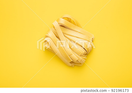 Uncooked pappardelle pasta on yellow background. Uncooked pappardelle pasta on yellow background. 92196173