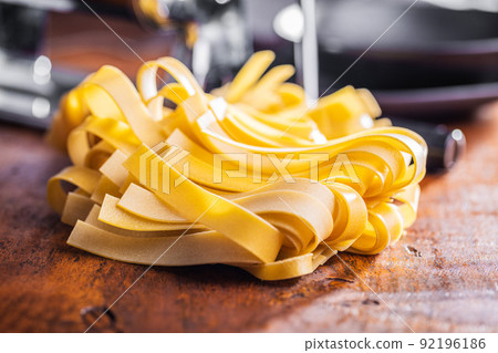 Uncooked pappardelle pasta on wooden table. 92196186