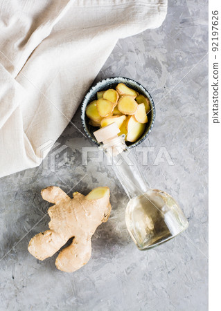 Bottle with natural ginger serum and chopped ginger in a bowl on the table. Natural care cosmetics. Top and vertical view 92197626