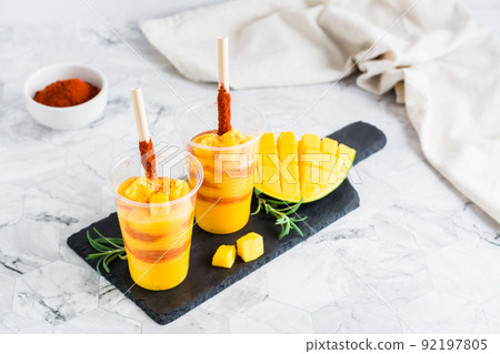 Mangonada mexican  smoothie from mango with chamoy sauce and tamarind straw in plastic glasses 92197805