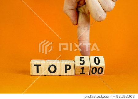 From Top 100 to 50 symbol. Businessman turns wooden cubes and changes concept words Top 100 to Top 50. Beautiful orange table and background. Business and from Top 100 to Top 50 concept. Copy space. From Top 100 to 50 symbol. Businessman turns wooden cubes and changes concept words Top 100 to Top 50. Beautiful orange table and background. Business and from Top 100 to Top 50 concept. Copy space. 92198308