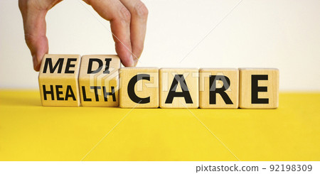 Medicare or healthcare symbol. Doctor turns cubes, changes the word 'healthcare' to 'medicare'. Beautiful yellow table, white background. Copy space. Medical, medicare or healthcare concept. 92198309