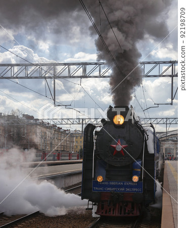 Black old Soviet steam locomotive with smoke and steam departs from the station. Black old Soviet steam locomotive with smoke and steam departs from the station. 92198709