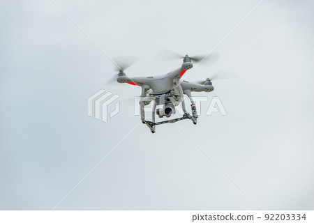 White quadrocopter in the sunset sky. 92203334