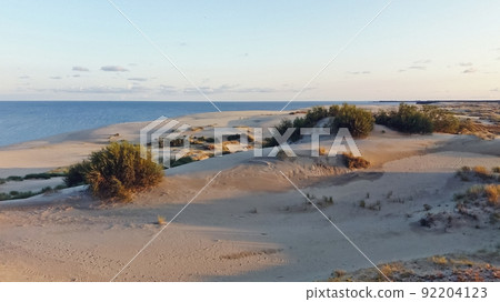 View of dunes and sea in light of setting sun 92204123