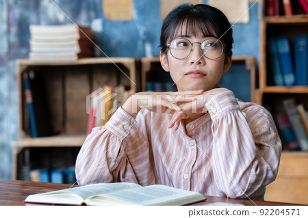 Young woman with glasses reading in the room 92204571