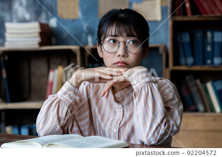戴眼鏡的年輕女子在房間裡看書 92204572