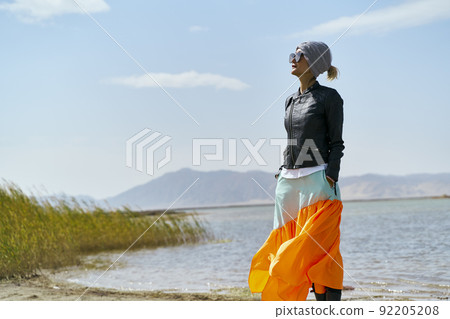 asian woman tourist standing by a lake looking at view under blue sky 92205208