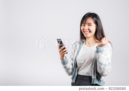 Woman excited holding mobile phone funky successful raise fists say yes 92208080