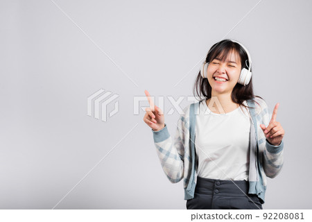 Woman excited smiling listening to music radio in bluetooth headphones and dancing with smartphone 92208081