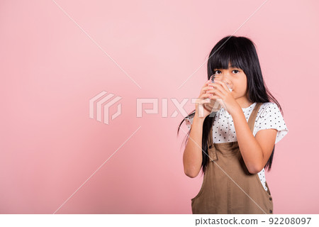 Asian little kid 10 years old smile hold milk glass drink white milk and drinking 92208097
