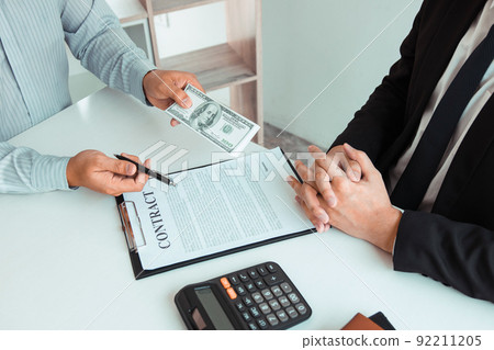 Partner has made a fraud in the contract of sale and being handed a cash and pen to the businessman signing the contract corruption bribery concept. Partner has made a fraud in the contract of sale and being handed a cash and pen to the businessman signing the contract corruption bribery concept. 92211205