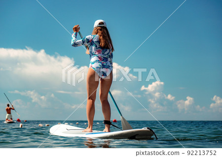 Woman sup sea. Happy healthy fit woman in bikini relaxing on a sup surfboard, floating on the clear turquoise sea water. Recreational Sports. Stand Up Paddle boarding. Summer fun, holidays travel. Woman sup sea. Happy healthy fit woman in bikini relaxing on a sup surfboard, floating on the clear turquoise sea water. Recreational Sports. Stand Up Paddle boarding. Summer fun, holidays travel. 92213752