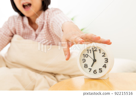 睡衣中年婦女睡在臥室的鬧鐘 92215516