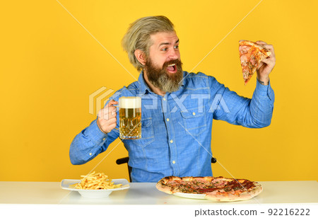French fries. guy in bar drinking beer glass and eating pizza.  92216222
