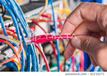 closeup of hand of administrator connecting network cable into switch closeup of hand of administrator connecting network cable into switch 92216271