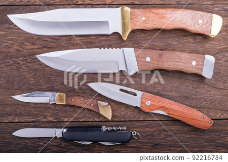Various outdoor knives on a wooden table 92216784