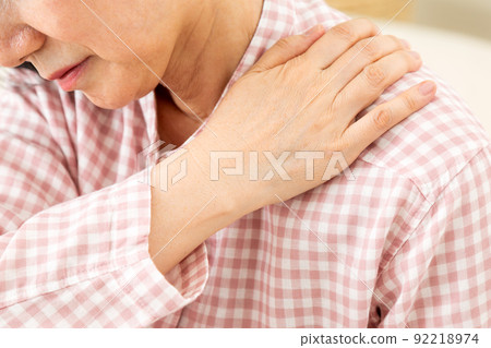 Middle-aged woman wearing pajamas and suffering from stiff shoulders in the bedroom 92218974
