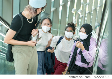 Group of young women laughing together as they take the escalator up a building. 92220998