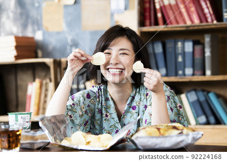 A woman eating potato chips 92224168
